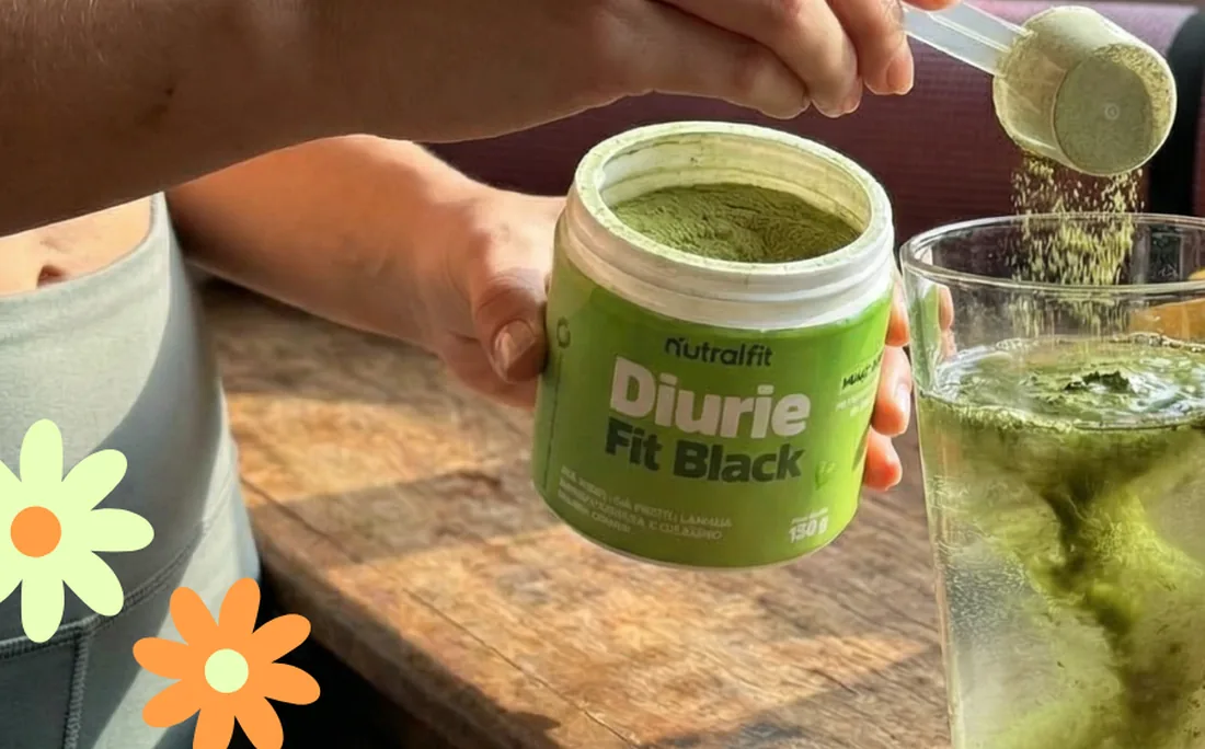 Uma m&atilde;o serve o p&oacute; de DiurieFit Black com o dosador num copo de &aacute;gua.